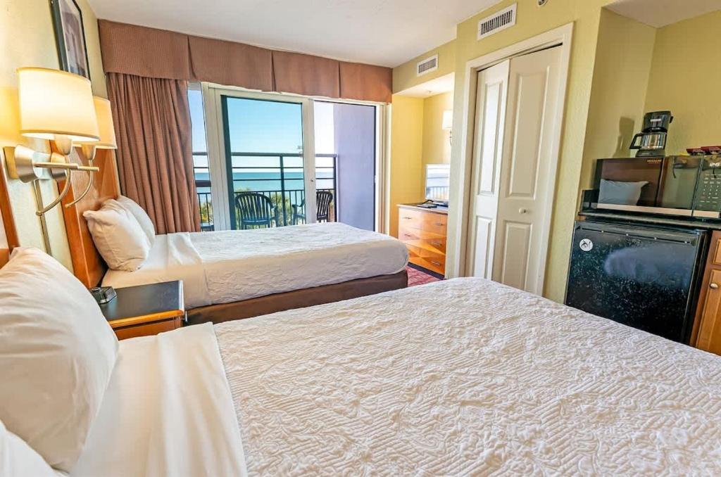 a hotel room with two beds and a balcony at Oceanfront Convenience on Lower Floor, Heated Pool in Myrtle Beach
