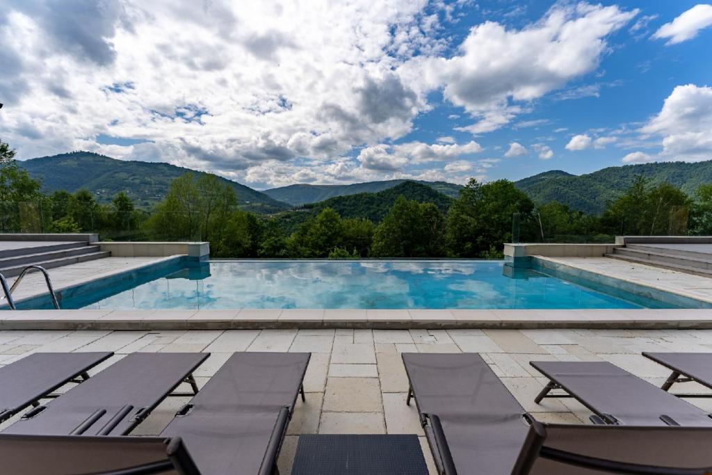 a swimming pool with chairs and mountains in the background at Cabanele CARMEL in Muntele Rece