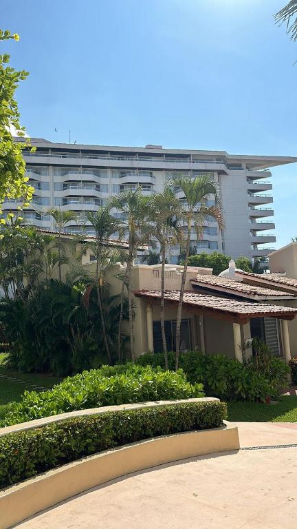a building with palm trees in front of a building at Villa 1 en Hotel Tesoro Ixtapa in Ixtapa