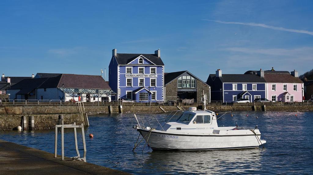 a white boat in the water in front of a house at Harbour View in Aberaeron