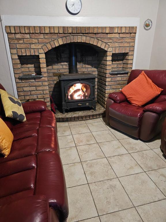 a fireplace with two leather couches and a fire place at John's Farmhouse in Kilrush
