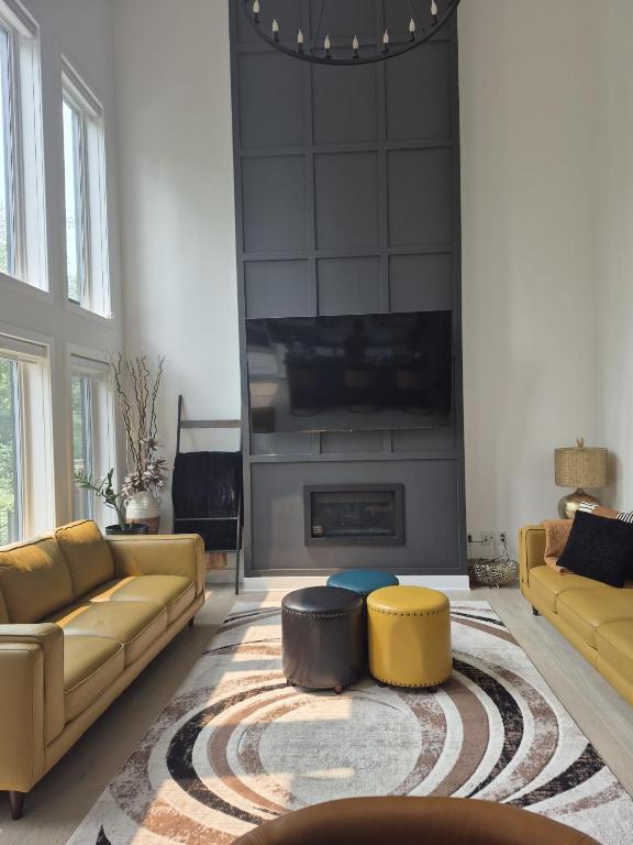a living room with yellow couches and a fireplace at The Creek Home in Kemptville