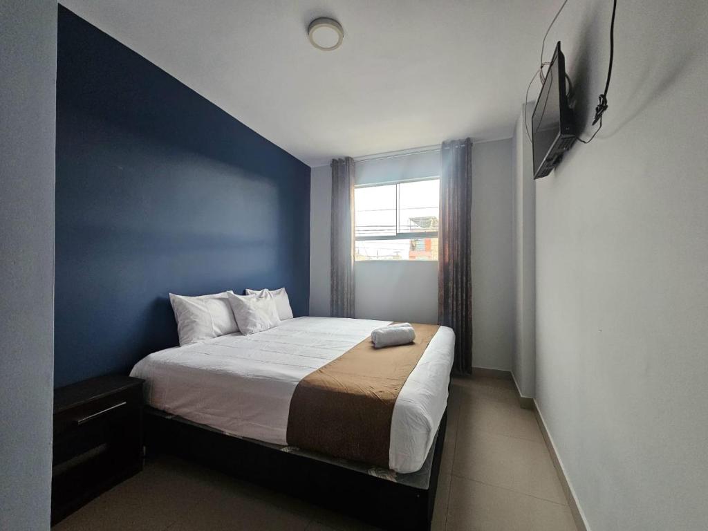 a bedroom with a large bed with a blue wall at Barlovento Business Hotel in Piura