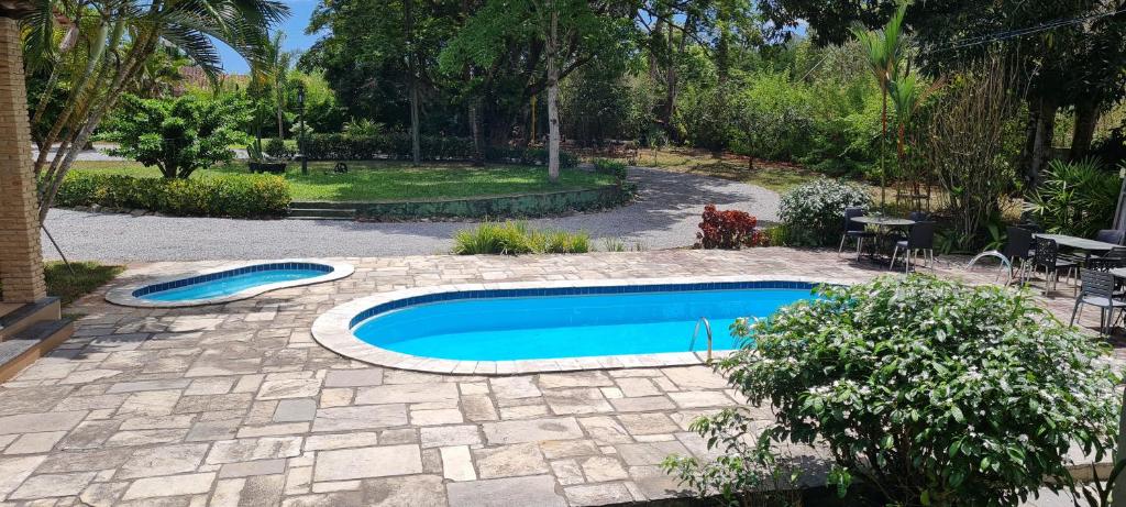 a swimming pool in a garden with a patio at Flat 02 Carvalhos de Aldeia in Recife