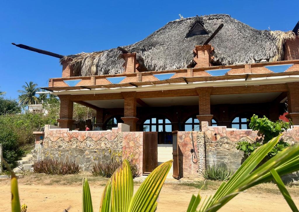 a large building with a thatched roof with at Beachfront - Private Floor, 4 Rooms - Casa 3 Lunas in Playa Agua Blanca