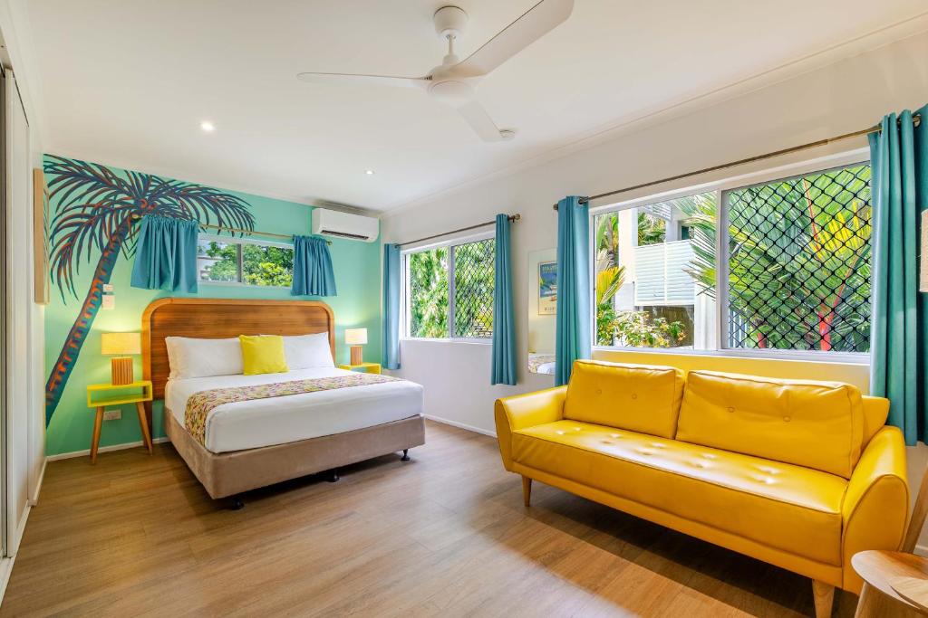 a bedroom with a bed and a yellow couch at Port Douglas Motel in Port Douglas