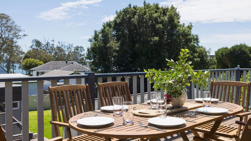 a wooden table with plates and glasses on a balcony at Port View on the Peninsula in Lemon Tree Passage