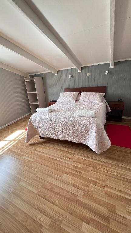 a bedroom with a bed and a wooden floor at Hospedaje Avenida in Puerto Montt