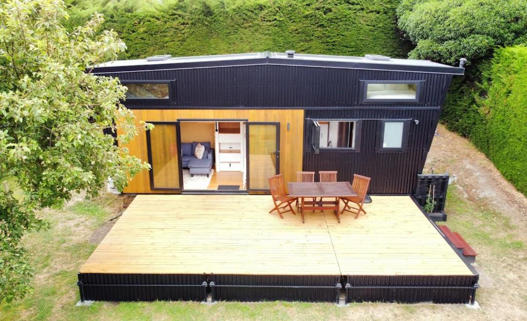 a tiny house with a table and chairs on a deck at The Tiny Diamond in Diamond Harbour