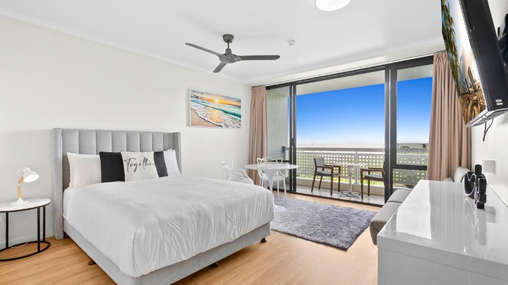 a white bedroom with a bed and a large window at The Studio at Northshore Tower in Cairns North