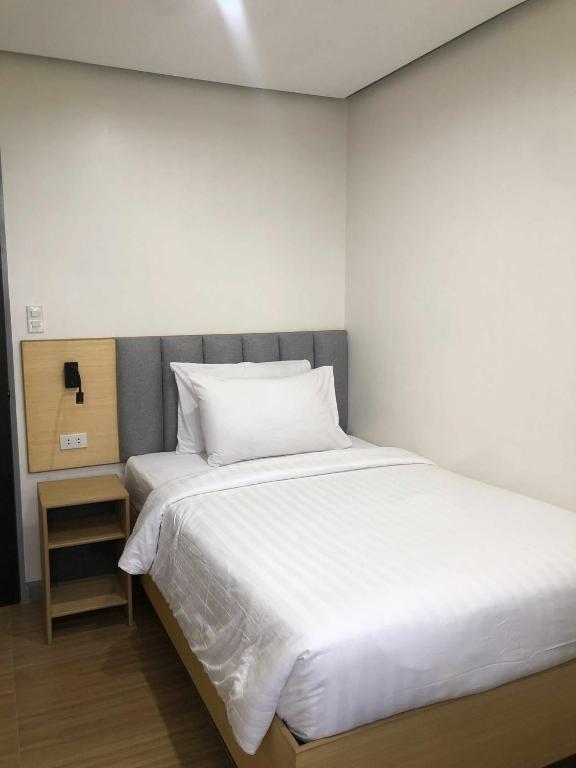 a bedroom with a large white bed and a night stand at GQ Apartment in Aklan