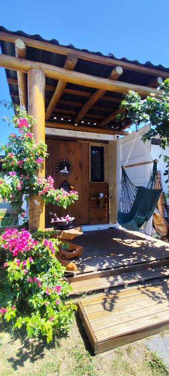 a hammock on a patio with flowers at Casa Brisa ar condicionado excelente banho a gás e acabamento premium próximo ao mar in Imbé