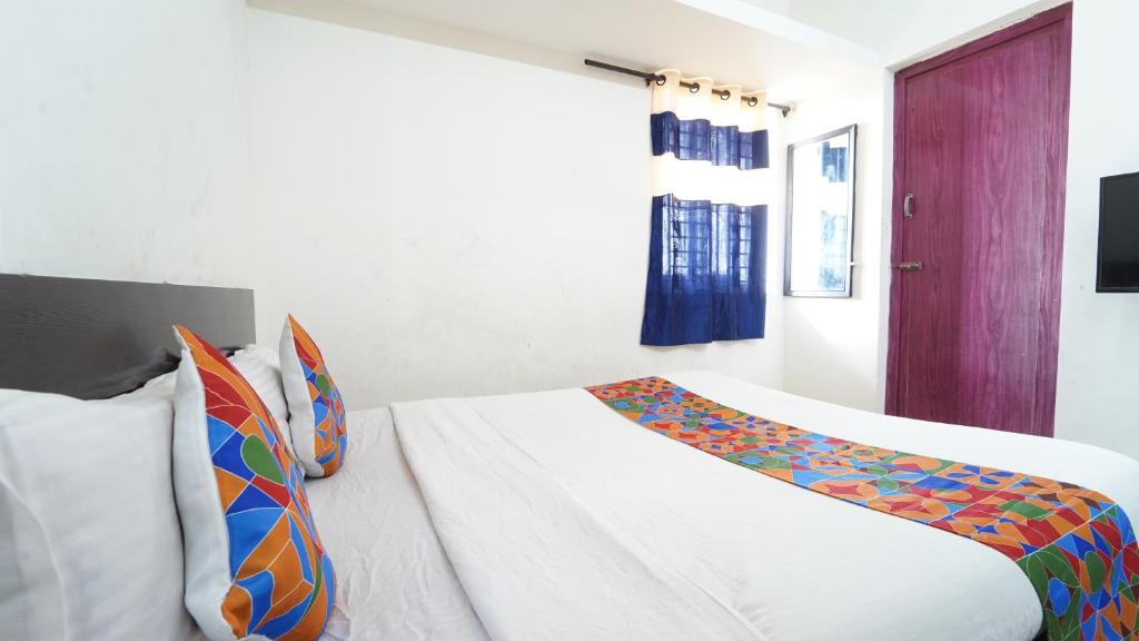 a bedroom with a white bed with a colorful blanket at Peelamedu PSG Tech Near Rooms in Coimbatore