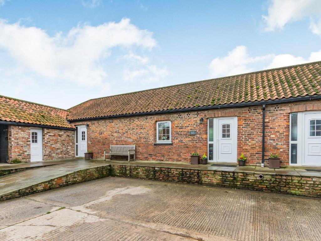 a brick building with a bench on a patio at Leedale Cottage in Saltmarshe