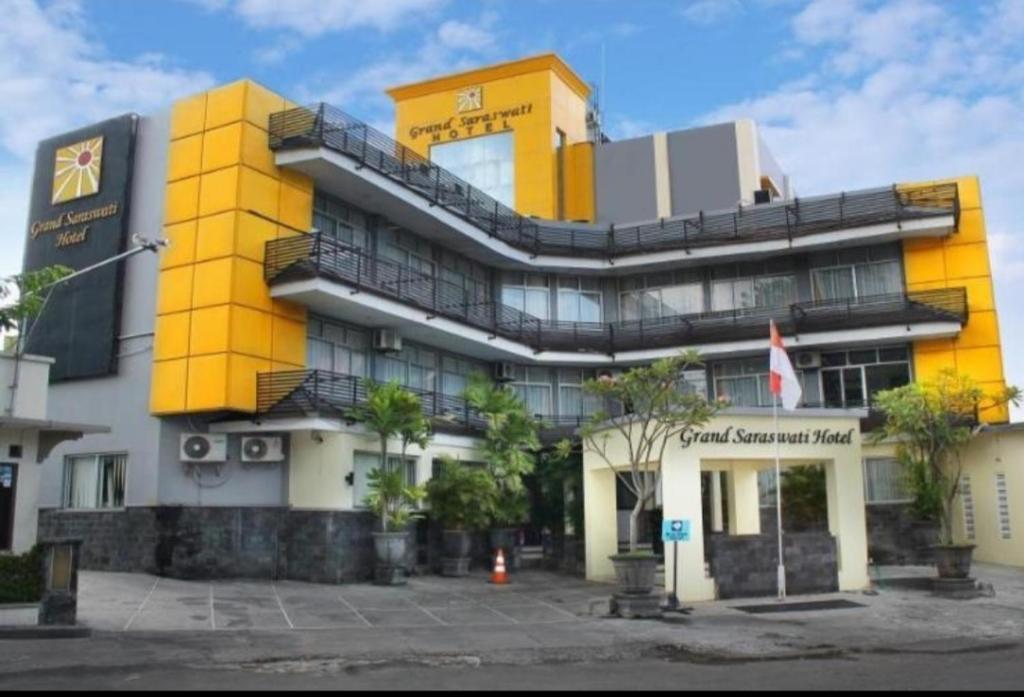 a yellow and white building with trees in front of it at Hotel GRANDSARASWATI in Stasiun Poncol