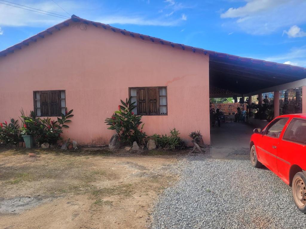 a red car parked in front of a pink house at Encanto da Rosa in Cavalcante