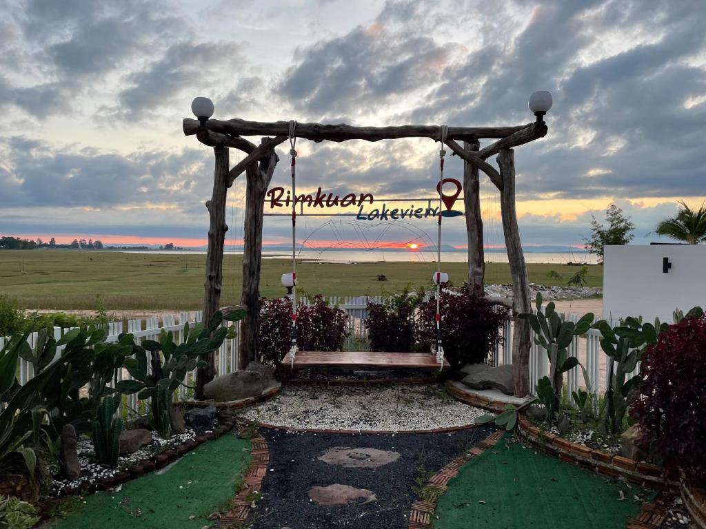 a wooden pergola with a sign in a garden at Rimkuan Lakeview in Ban Kham Kom