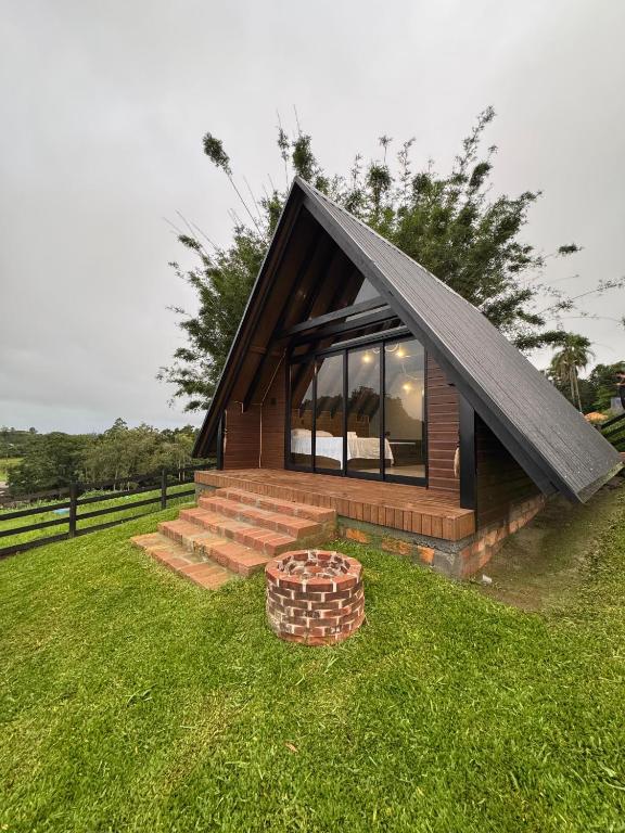 a small house with a black roof on the grass at Refúgio do Morro - Cabana 1 in Torres