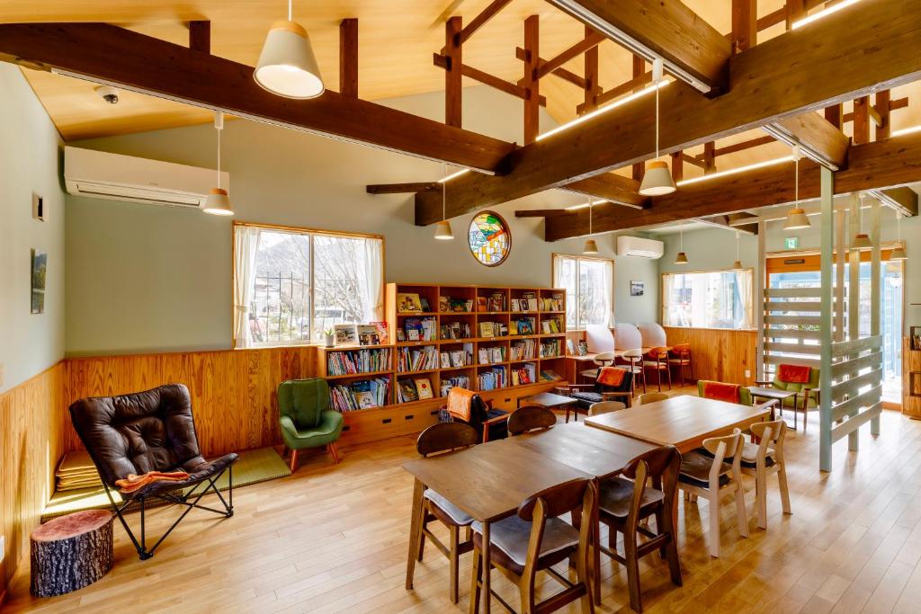 a library with wooden tables and chairs and bookshelves at 宿と図書サロン 花車 Hanagurum Inn in Amakusa