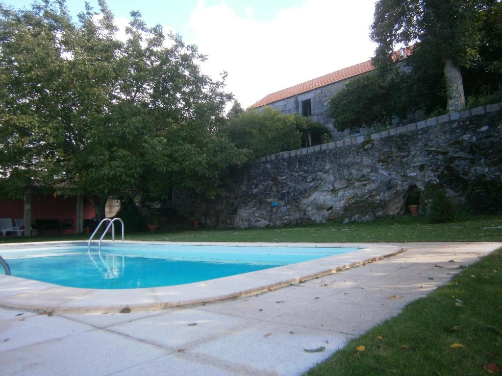 una piscina in un cortile accanto a un muro di pietra di Casa da Costinha a Cinfães