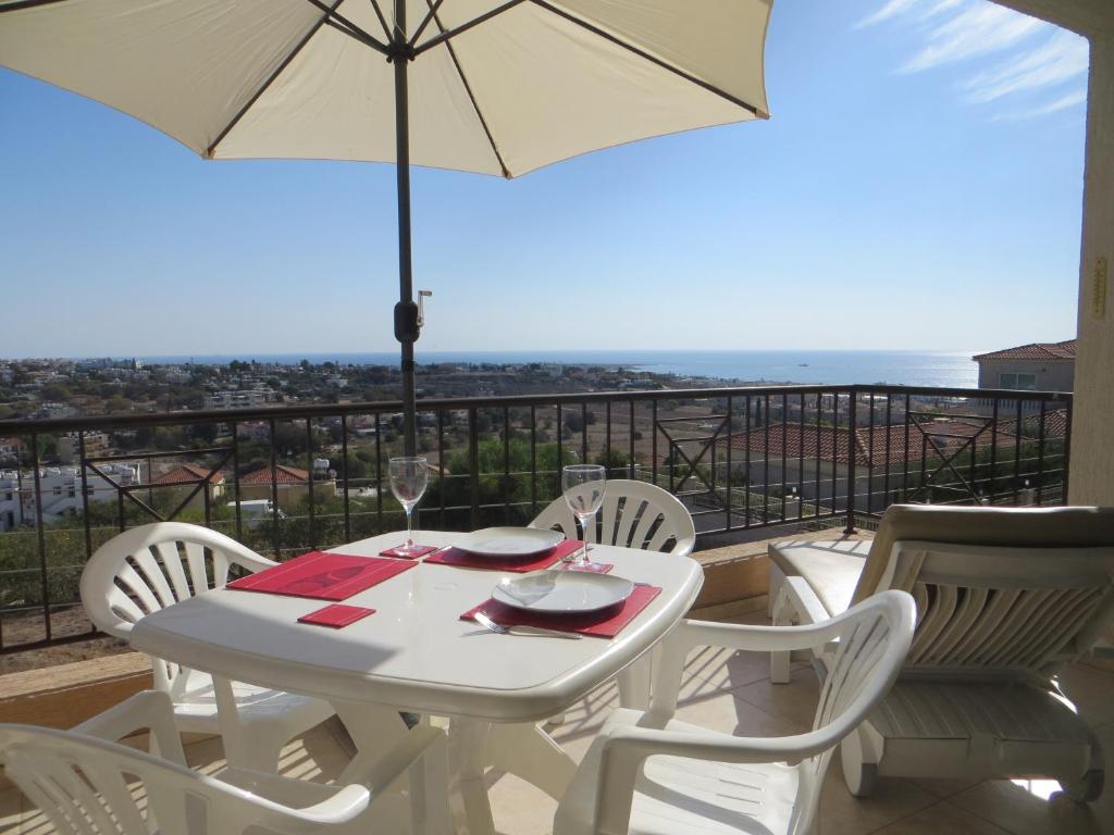 a white table and chairs with an umbrella on a balcony at Melania Apartment in Paphos City