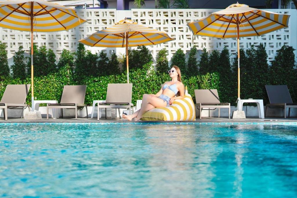 a woman sitting on a pool noodle next to a swimming pool at Fourium Pattaya Hotel and Serviced Residence in Pattaya South