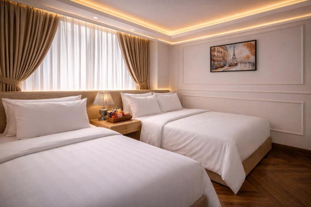 a hotel room with two beds and a window at Vũ Ngọc Hotel Núi Sam in Chau Doc