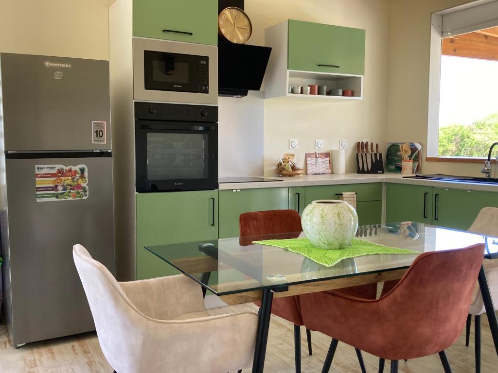 a kitchen with green cabinets and a glass table and chairs at La villa Surette in Capesterre