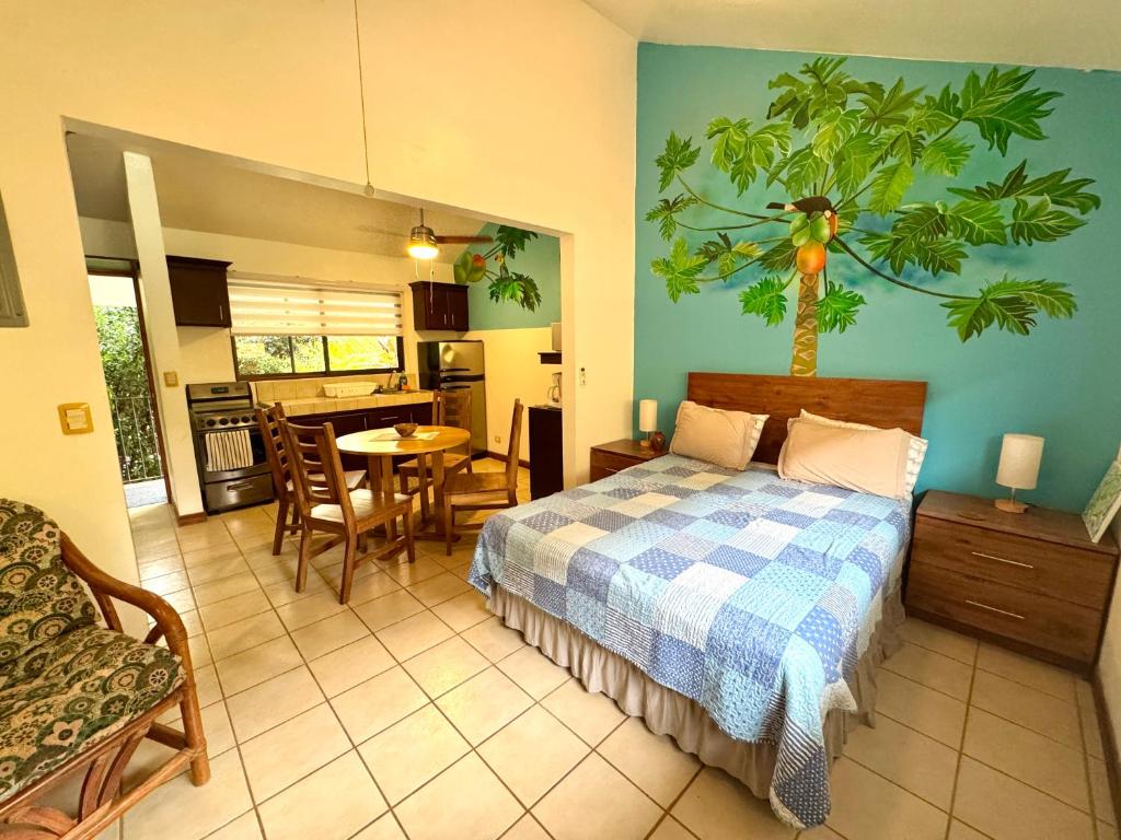 a bedroom with a bed and a table and a kitchen at Calm & Palms Second Floor Studio in Coco