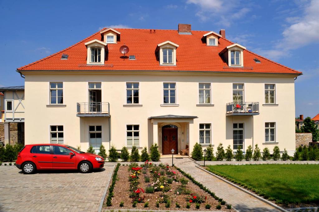 ein rotes Auto, das vor einem großen Haus parkt in der Unterkunft Appartements Residenz Jacobs in Ballenstedt