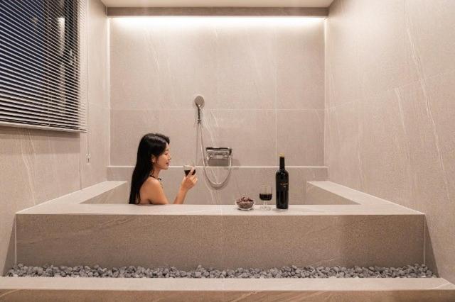 a woman sitting in a bath tub brushing her teeth at Brown Dot Hotel Incheon Bupyeong in Incheon