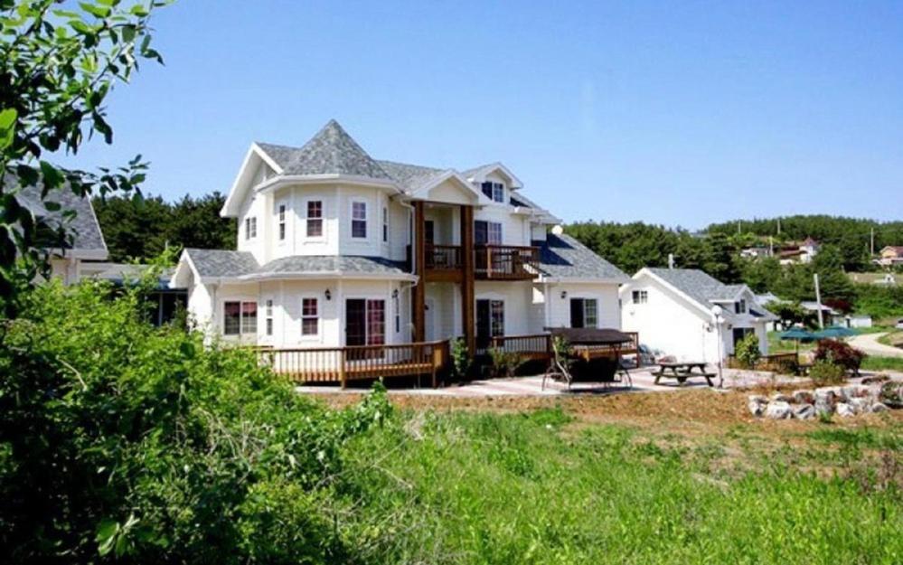 a large white house with a porch and a yard at Taean Mong And Mong Pension in Taean