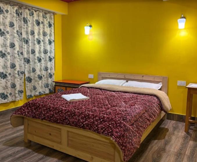 a bedroom with a large bed with a yellow wall at Hotel Sonam Chen Residency Lachung in Lachung