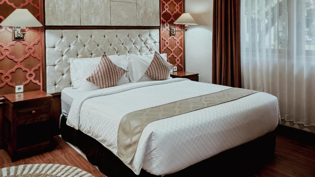 a bedroom with a large white bed with pillows at Royal Brongto Hotel in Yogyakarta