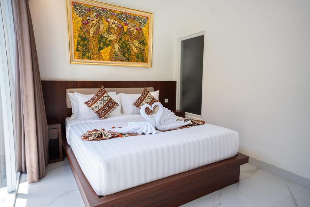 a bedroom with a bed with a painting on the wall at Lumbung Sari Studio in Ngurah Rai International Airport