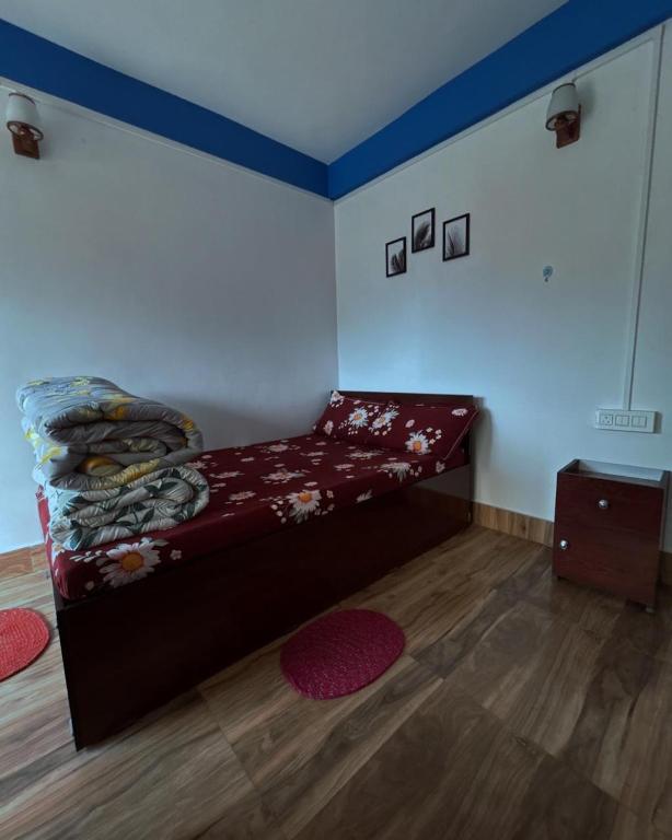 a room with a bed in a room with wood floors at Padma Riverside Homestay Tabakoshi in Mirik