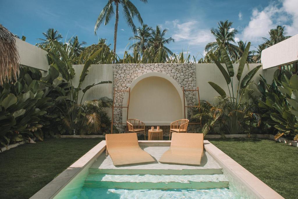 a backyard with two chairs and a swimming pool at Baiana Beach Villas in General Luna