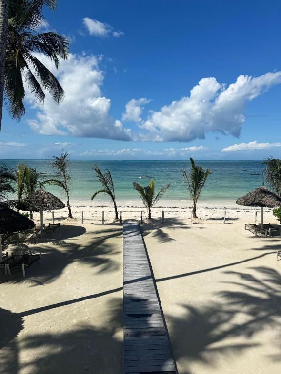 a beach with chairs and umbrellas and the ocean at Tremendo Beachfront Apartment in Kiwengwa
