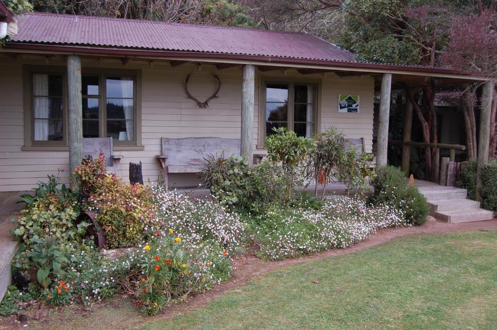 a small house with flowers in front of it at Wheatly Downs Farmstay and Backpackers in Hawera