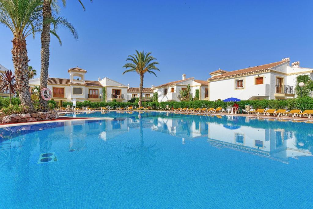 una gran piscina con palmeras y casas en Infinity Beach Resort Vera, en Vera