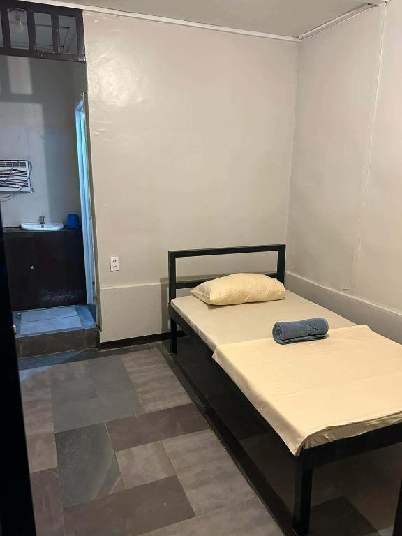 a small room with a bed and a bathroom at Little John's Town Inn in Coron