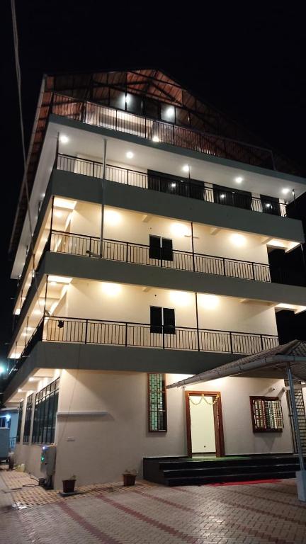 a lit up building with balconies on it at night at Sansav Garden Resort in Gurpur