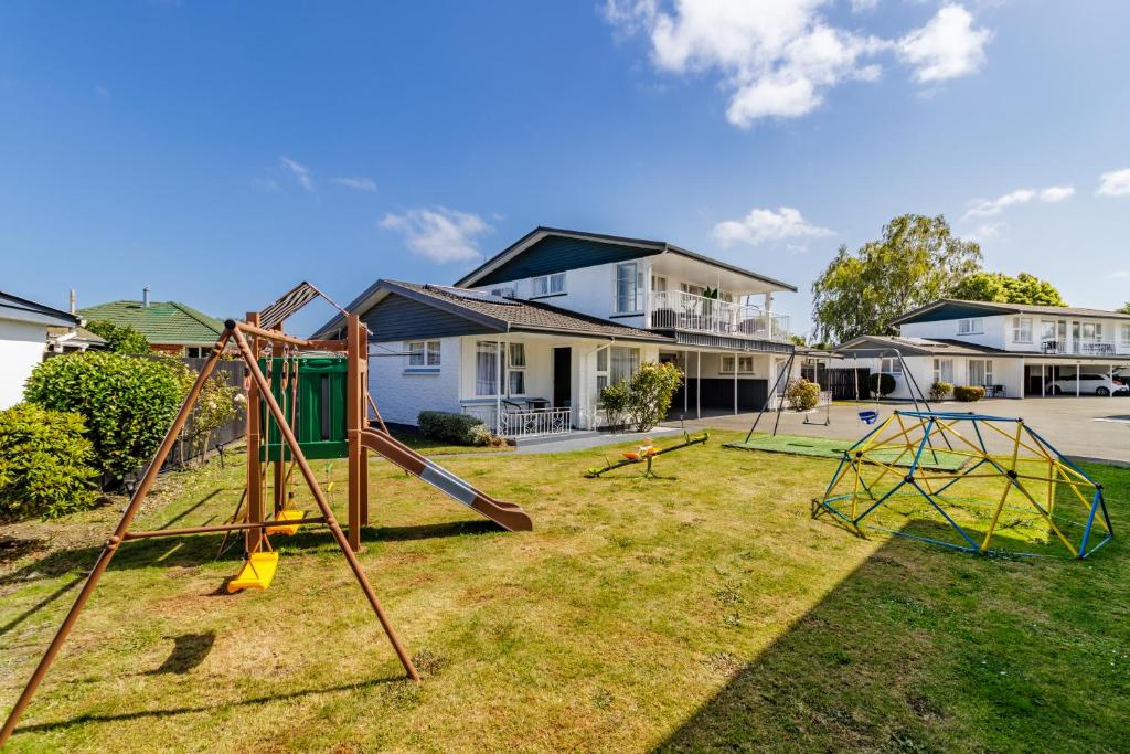 a yard with playground equipment in front of a house at Belle Bonne Motel in Christchurch