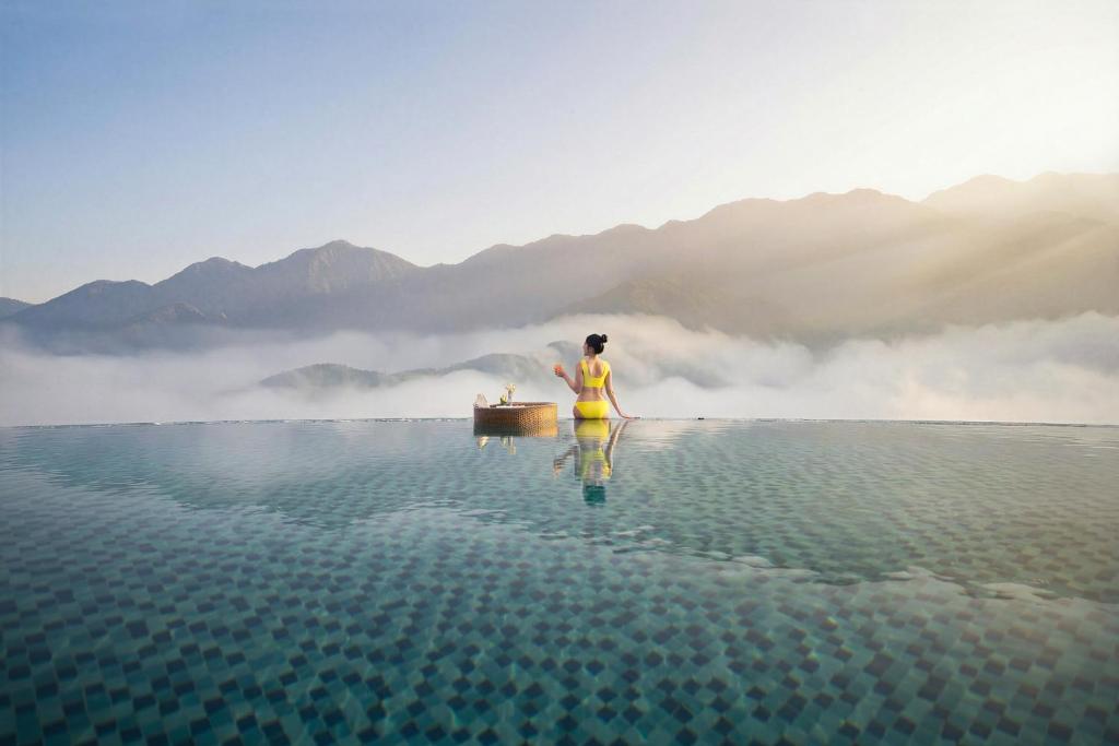 a person standing in the water with a boat at DeLaMont Sapa Hotel - Hill Serenity Retreat in Sapa