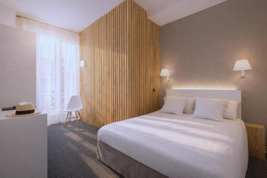 a bedroom with a large white bed and a window at Hôtel La Villa Tosca in Cannes