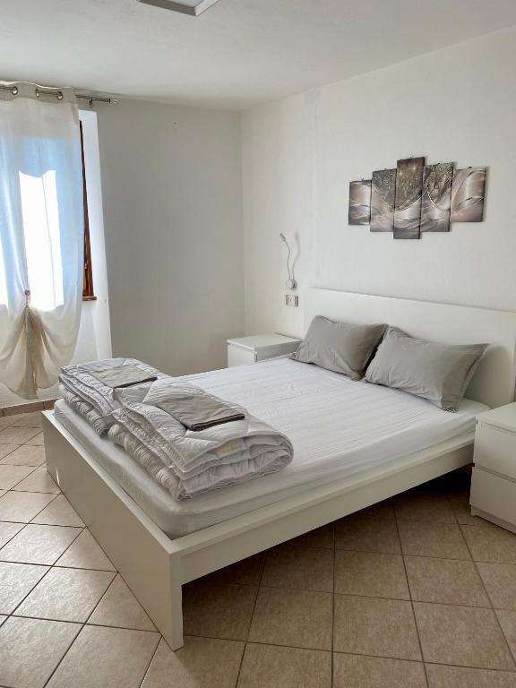 a large white bed in a room with a window at Casa Piccola in Tremosine Sul Garda