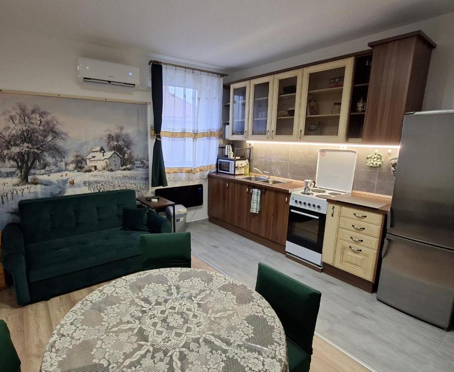 a kitchen with a green couch and a table at Tiszti Szálló Apartman in Verpelét
