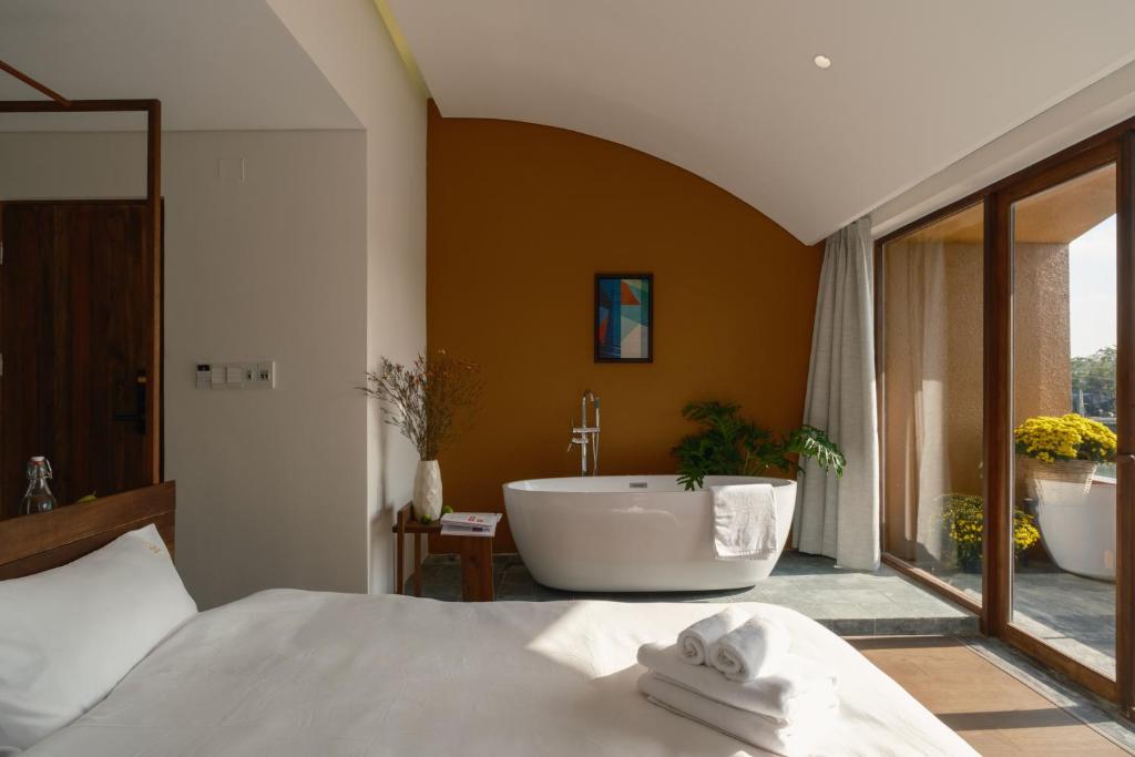 a bathroom with a bath tub and a bed at Amea Homestay in Thôn Kim Long (1)