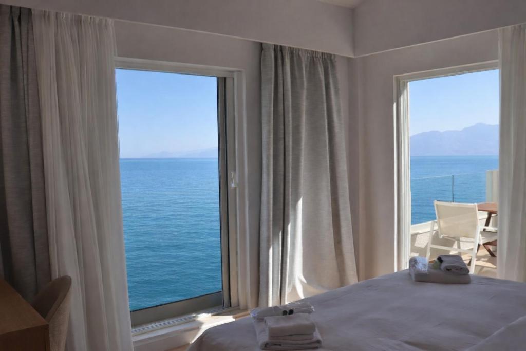 a bedroom with a large window looking out at the ocean at 9 Muses Apartments in Agios Nikolaos