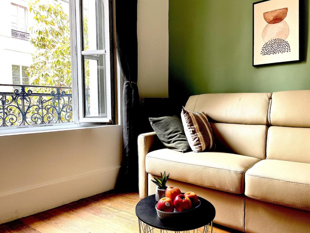 a living room with a couch and a bowl of fruit on a table at Charmant studio aux beaux volumes in Dreux